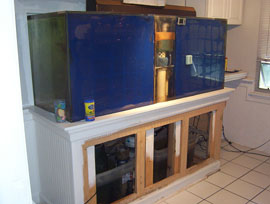rear view of 300 gal tank that is built into living my room wall. Acrylic 300 gal Marine, fish only, on a home made 2"x6" wood framed stand. Lighting consisting of two (2) 175 Metal Halide Pendant Fixtures (that have been removed to be rebuilt) with two (